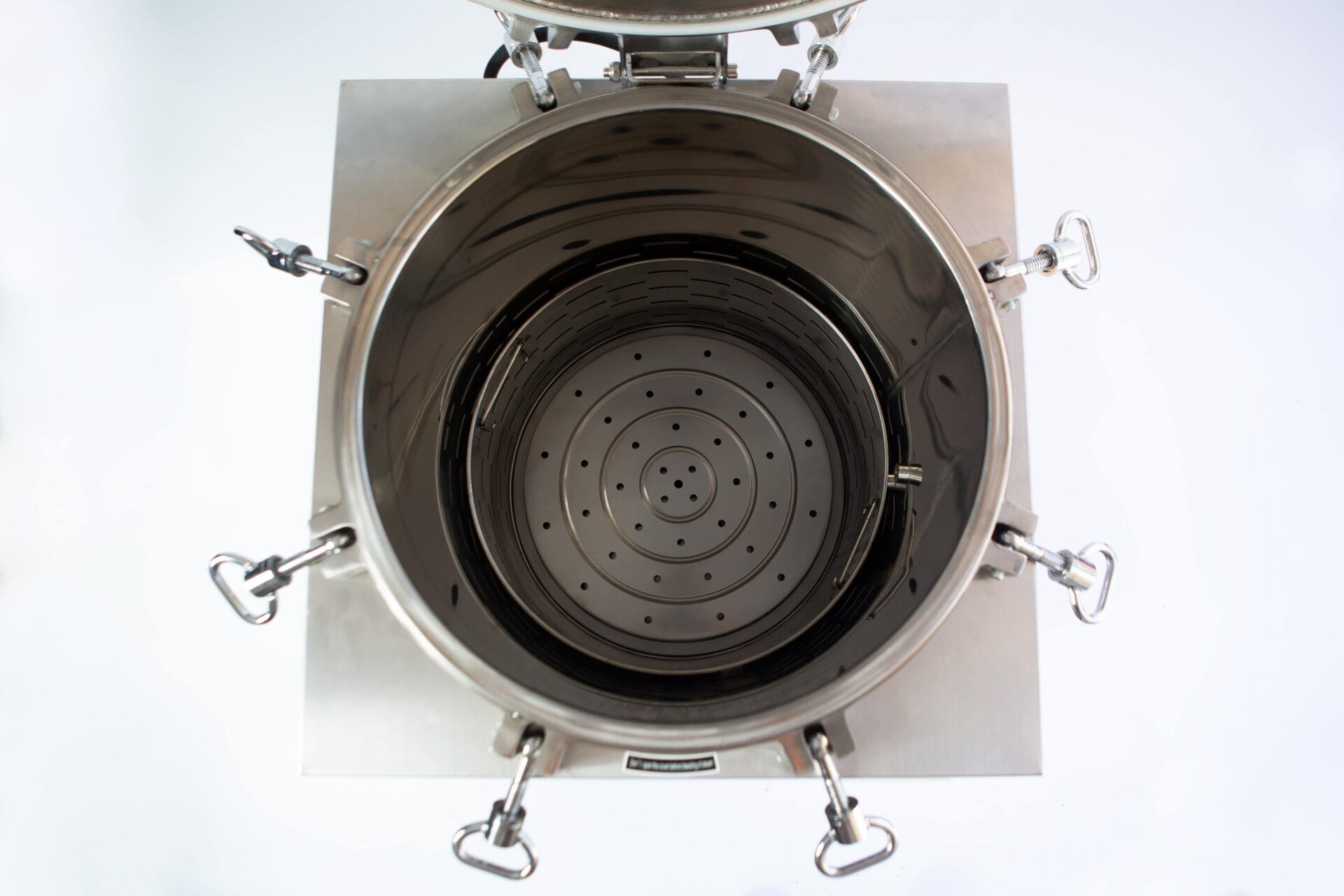 Top view of an open, empty stainless steel industrial container with clamps and a perforated bottom.