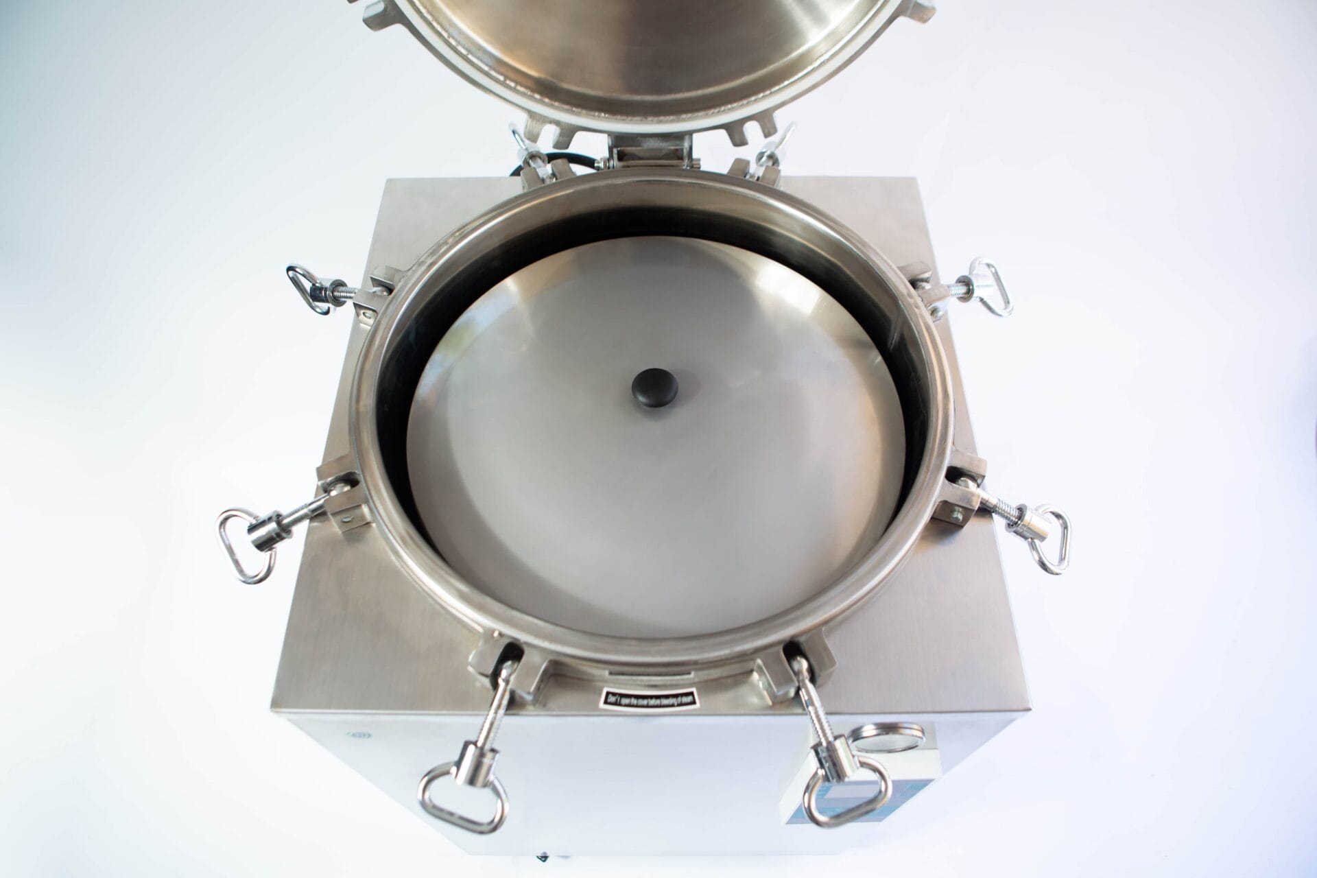 Open stainless steel autoclave with lid lifted, showing the circular inner chamber and locking clips.