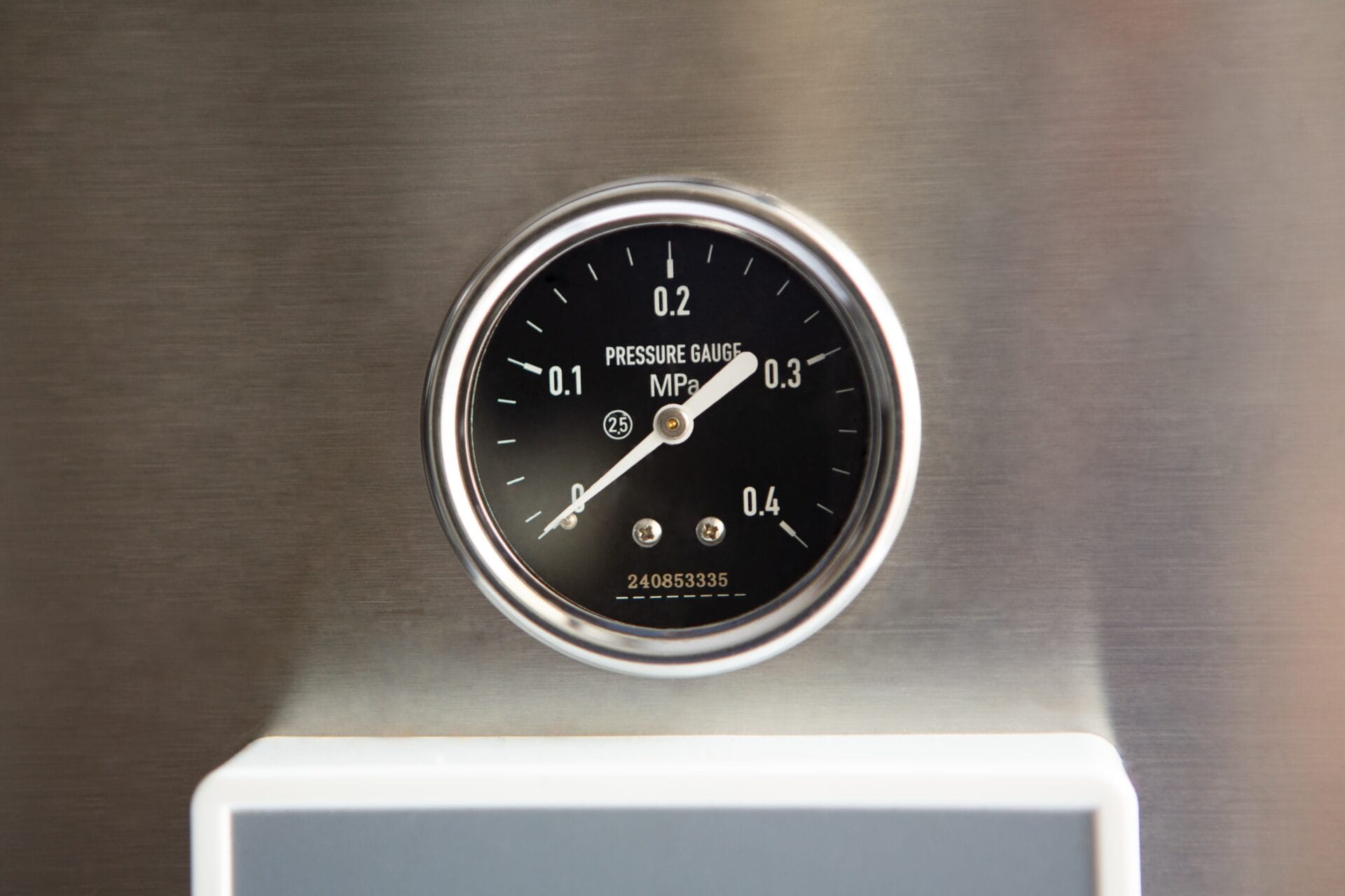 A close-up of a round black pressure gauge displaying measurements in MPa on a metallic surface.