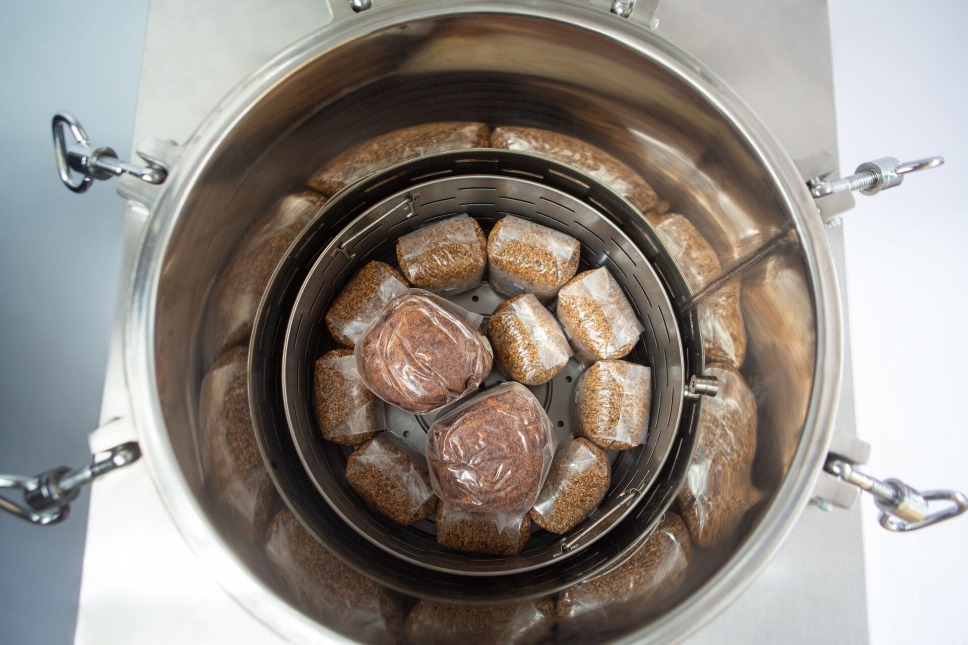 Top view of plastic-wrapped food bundles arranged inside a stainless steel container.