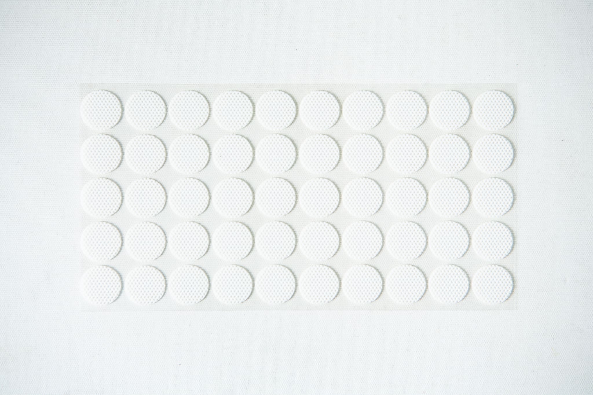 A sheet of small, round, white adhesive stickers arranged in a grid pattern on a white background.