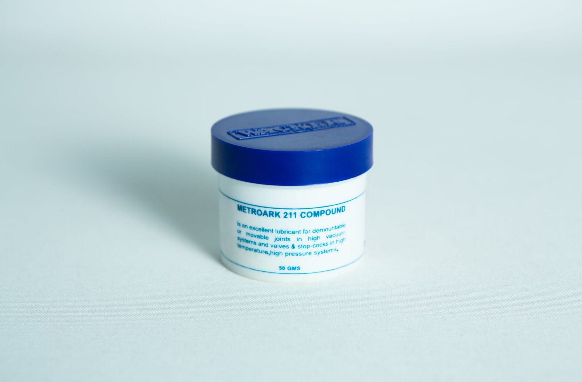 White jar with blue lid labelled "Silicone Grease Lubricant High Temp Vacuum – Metroark," used as a lubricant for mechanical parts.