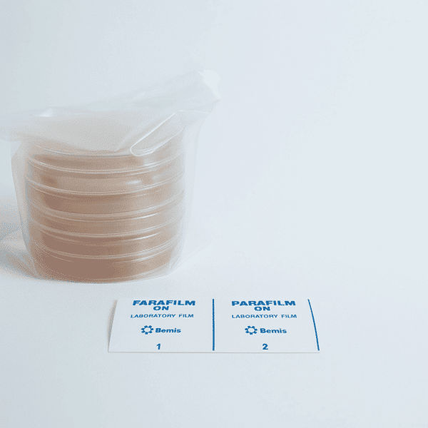 A stack of 5 MEA and 5 MEAG pre-poured 90mm agar plates, along with two Parafilm laboratory film labels, rest on a white surface.