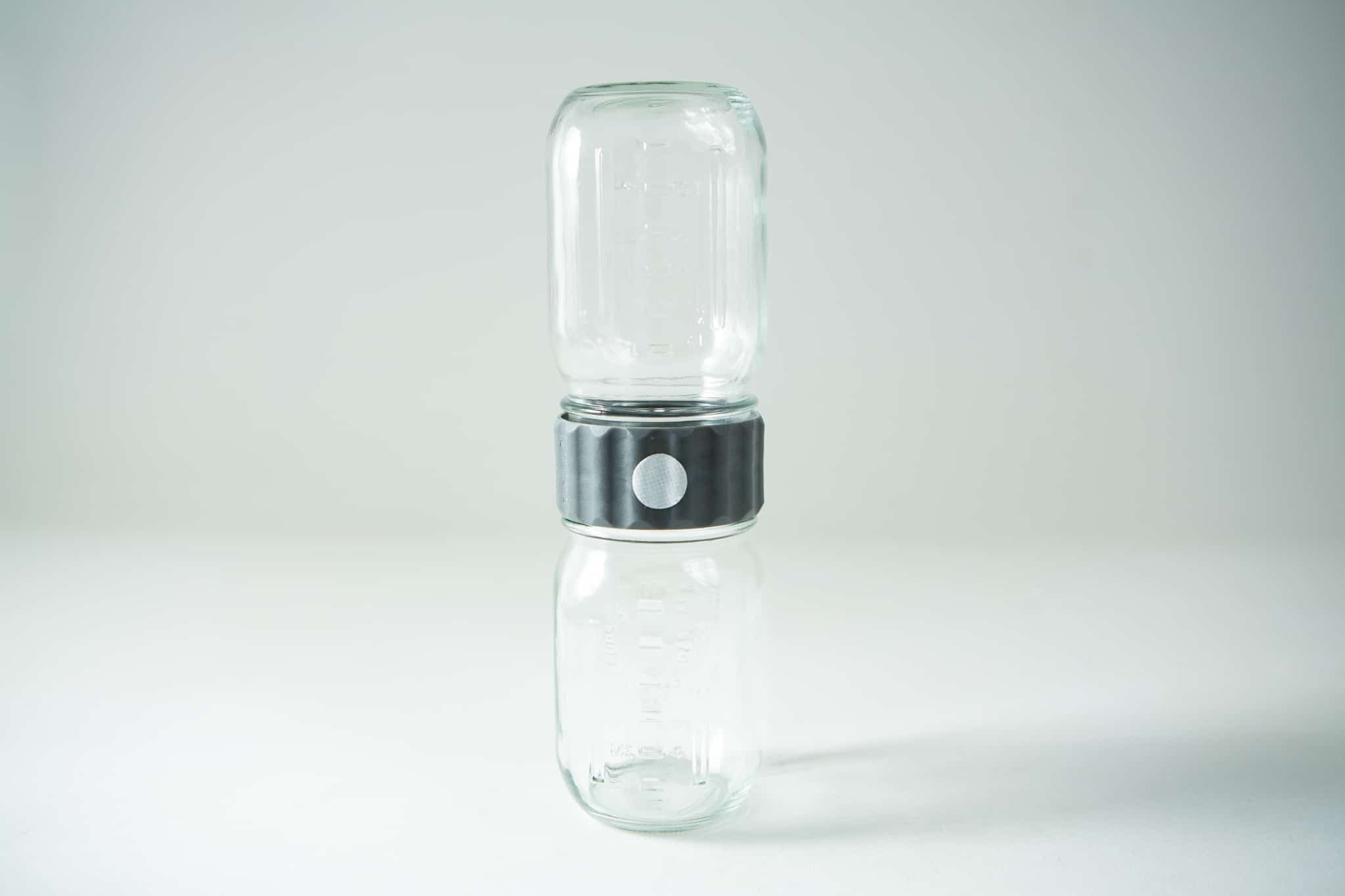 Two glass jars are stacked vertically, connected by a black and silver adaptor in the centre.