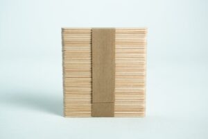 A bundle of ice lolly sticks, neatly wrapped with a brown paper band, is set against a white background.