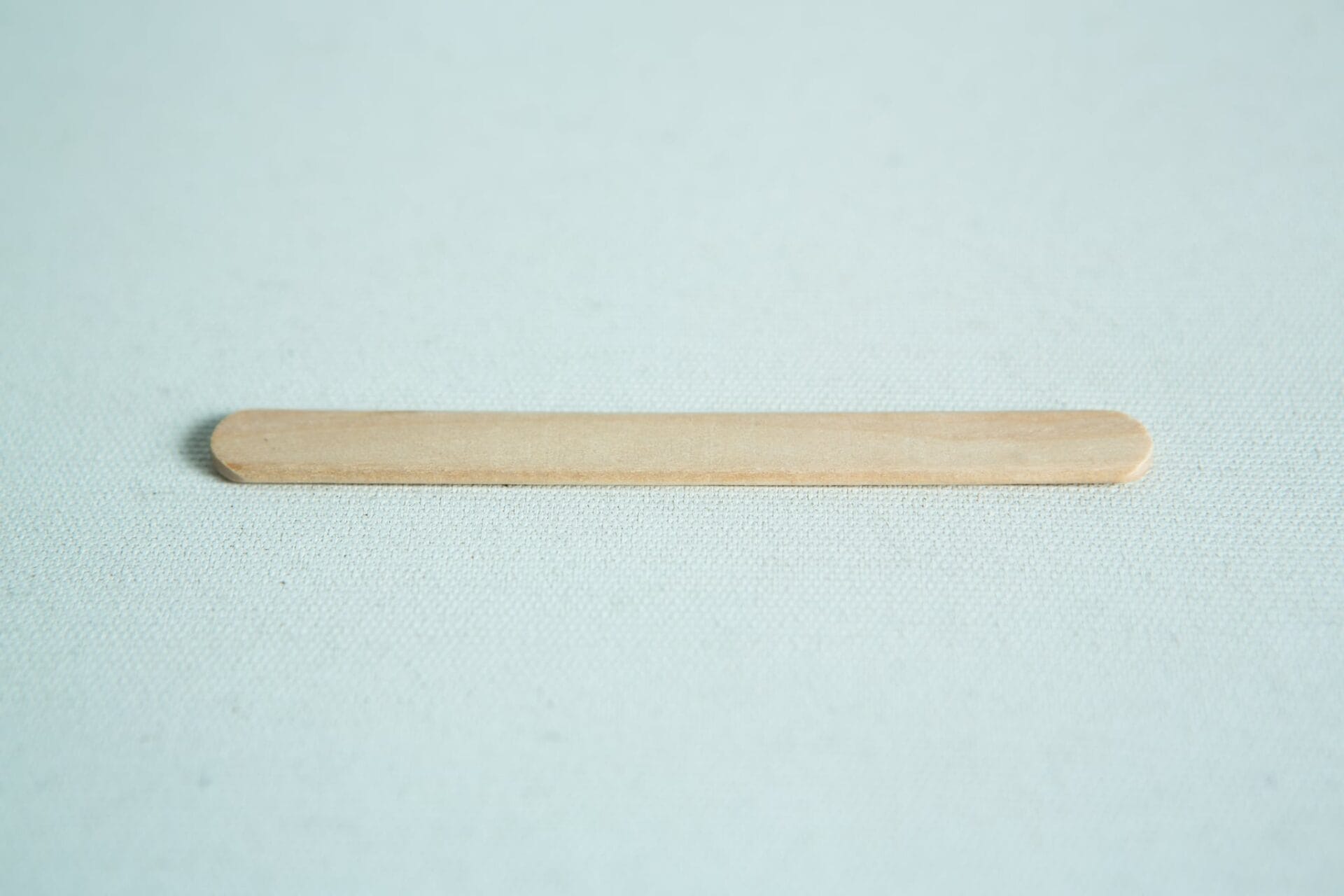 A Paddle Pop stick rests flat on a lightly textured surface.
