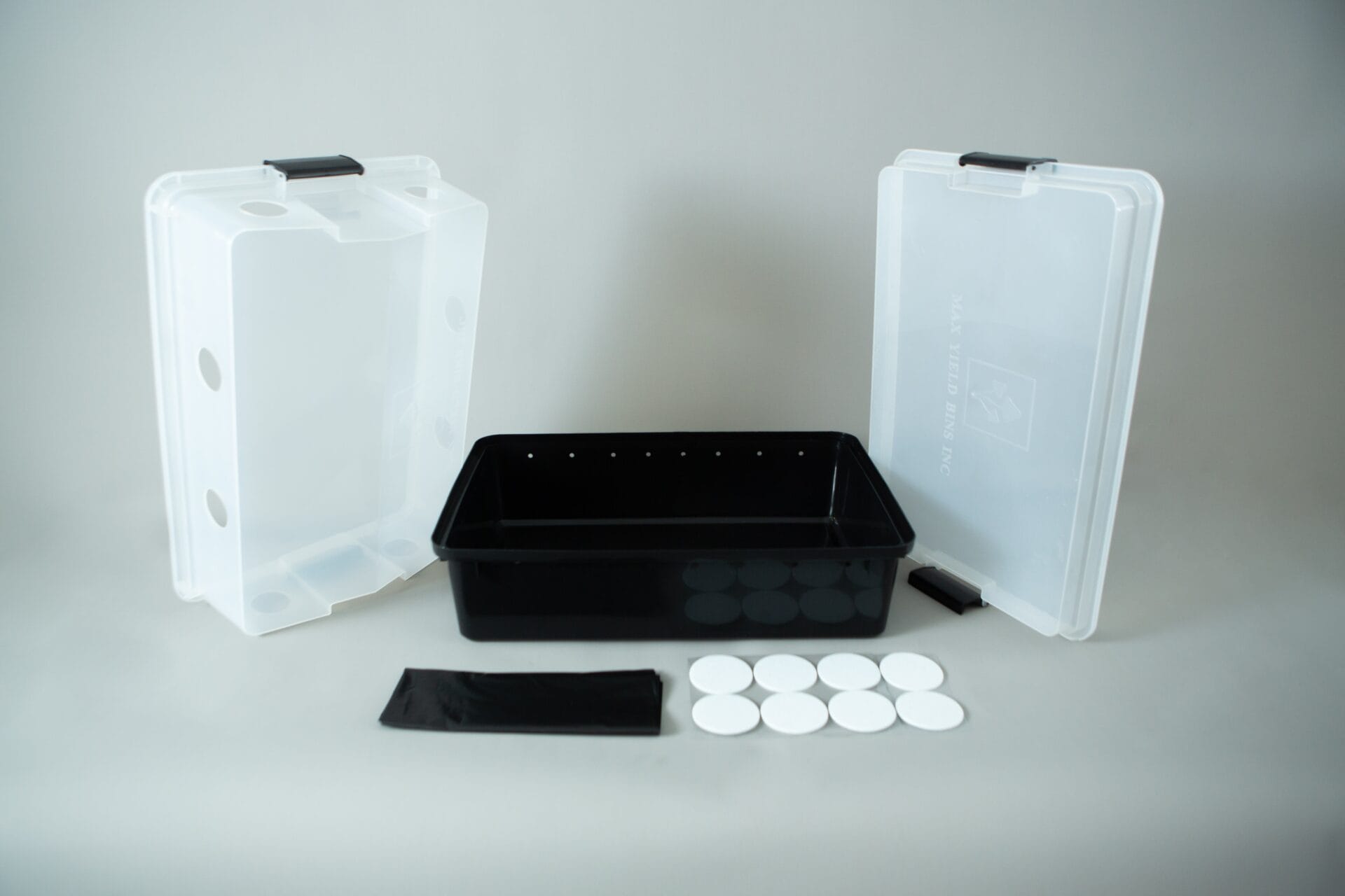 Plastic mushroom growing kit with a black tray, Colonisation Lid, two clear lids, filter discs, and a black filter patch—ideal for growing mushrooms at home.