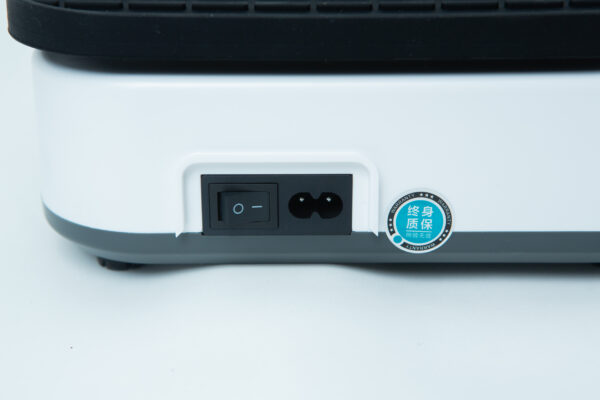Close-up of a power switch and socket on a white and grey electronic device, with a blue sticker beside them.