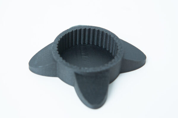 A black, round, 3D-printed object with three flat, fin-like extensions on a white background.