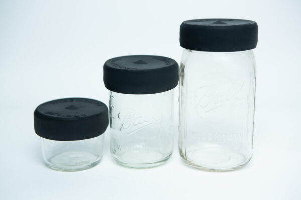 Three empty wide-mouth glass jars of different sizes with Silicone Mason Jar Rubber Lids, arranged side by side on a white background.