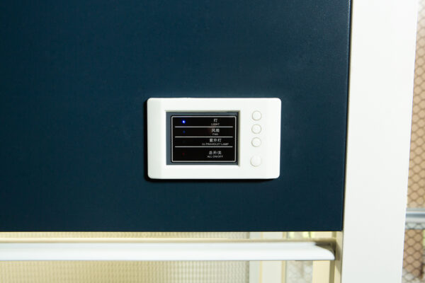 A wall-mounted digital control panel with buttons and a small display screen showing text in Japanese.